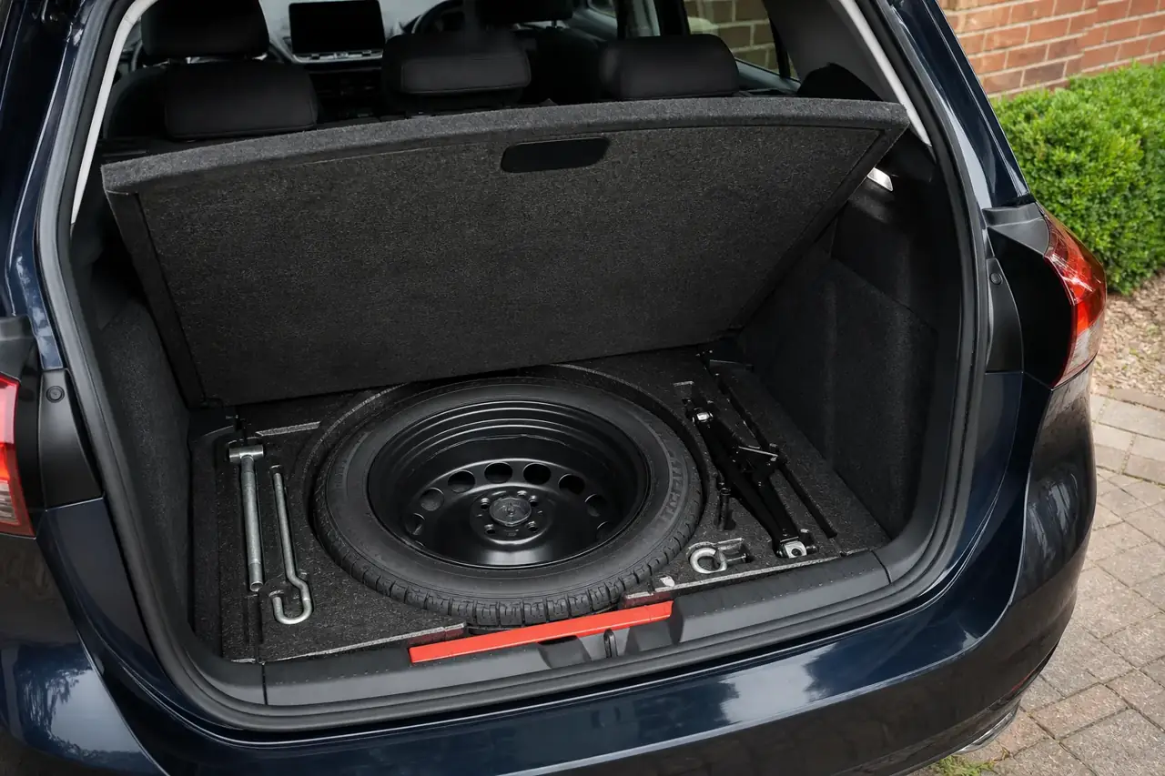 A spare wheel and tyre-changing tools stored beneath a boot floor